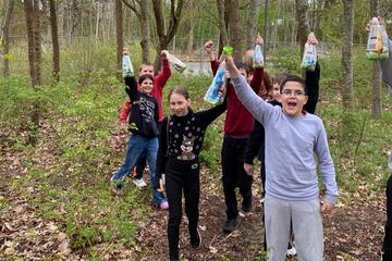 Mehrere Jugendliche gehen im Freien auf die Kamera zu und halten ihre "Beute", tüten mit Ostereiern, hoch.