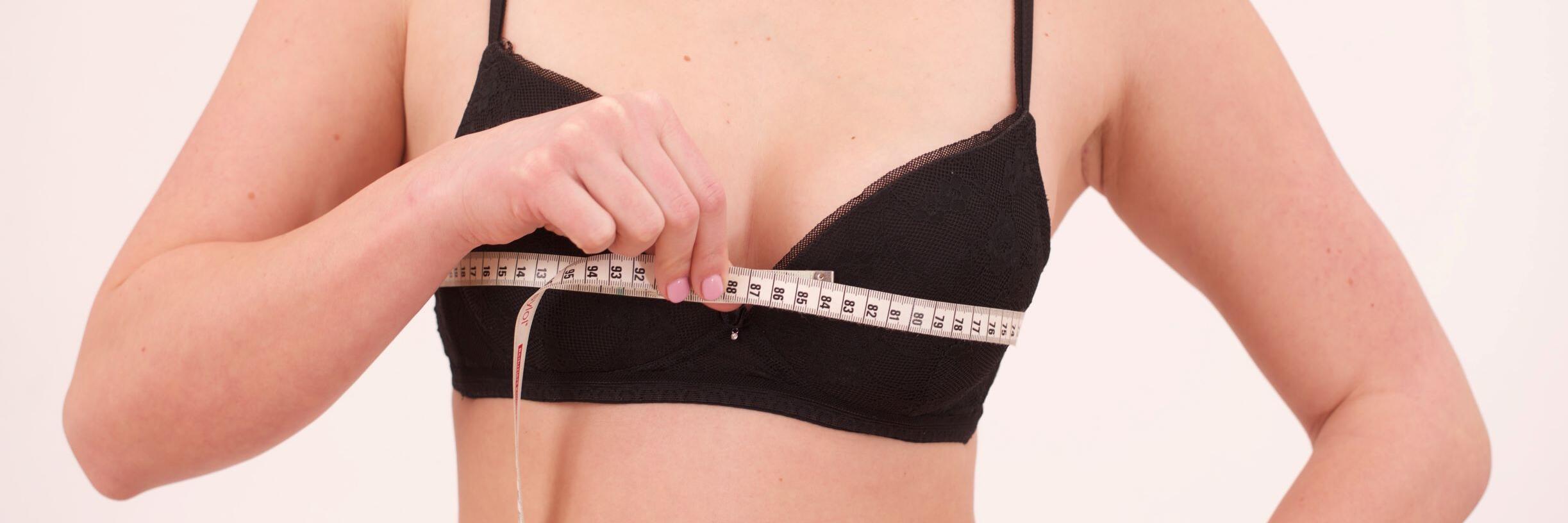 Frau, die mit Maßband ihren Brustumfang misst 