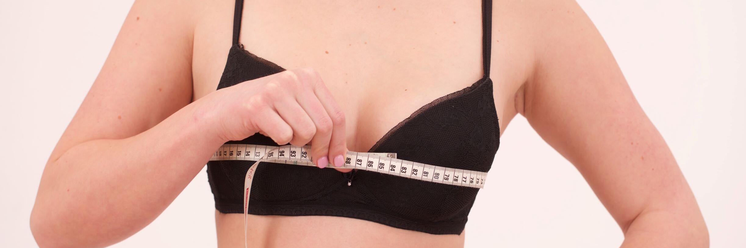 Frau, die mit Maßband ihren Brustumfang misst 