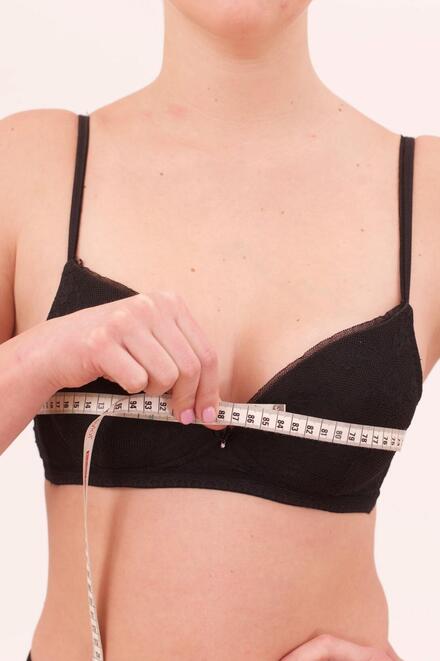 Frau, die mit Maßband ihren Brustumfang misst 