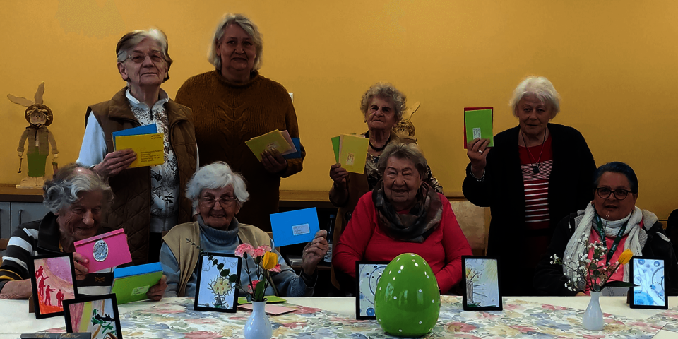 acht stehende und sitzende Menschen zeigen Osterpost