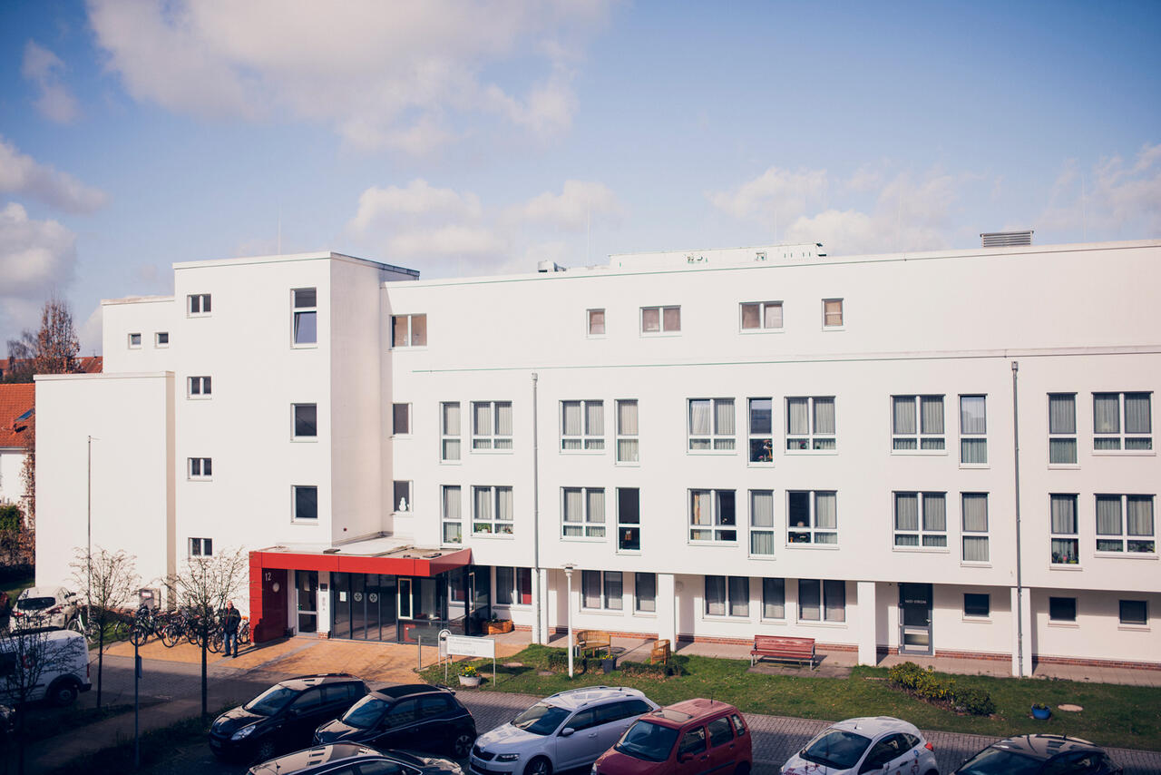 Einrichtung Johanniter-Quartier Lübeck, weißes mehrstöckiges Gebäude mit rotem Dach im Eingangsbereich