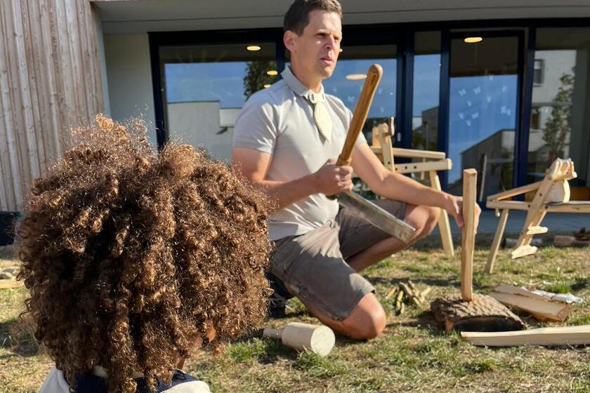 Ein Holzkünstler zeigt Kindergartenkindern, wie man den Werkstoff Holz bearbeitet.