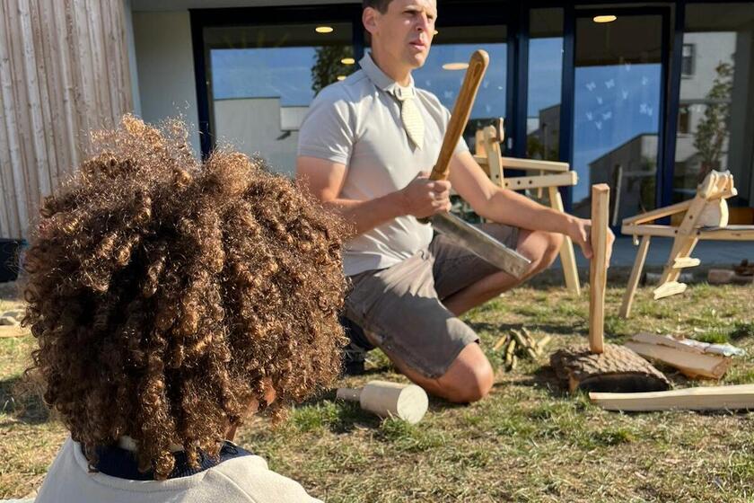 Ein Holzkünstler zeigt Kindergartenkindern, wie man den Werkstoff Holz bearbeitet.