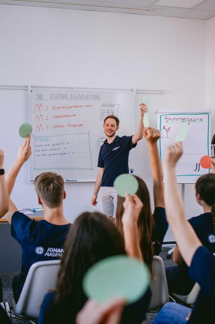 Mitglieder der Johanniter-Jugend stimmen bei einer Wahl mit Handzeichen ab.