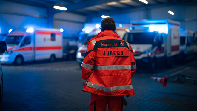 Eine Einsatzkraft der Johanniter-Jugend steht in der Fahrzeughalle der Johanniter in Wiesbaden.