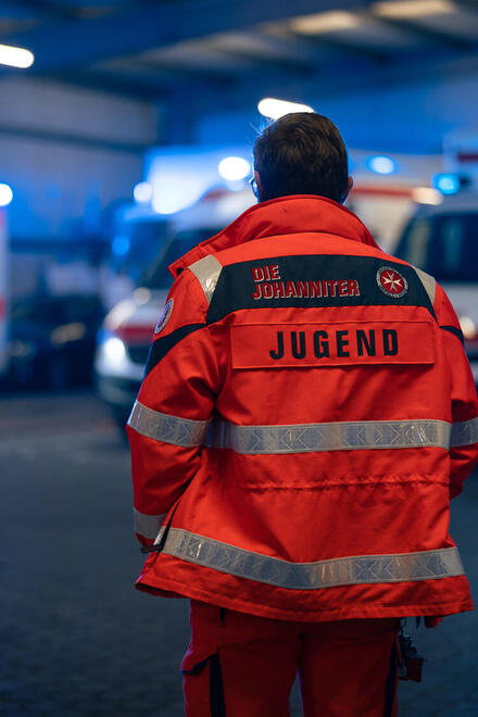 Eine Einsatzkraft der Johanniter-Jugend steht in der Fahrzeughalle der Johanniter in Wiesbaden.