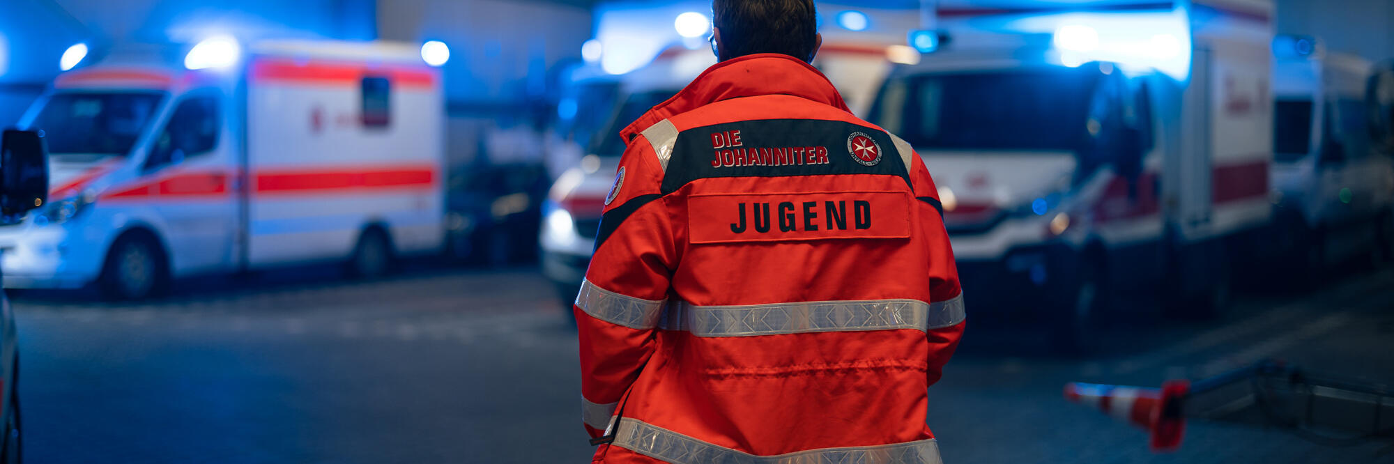 Eine Einsatzkraft der Johanniter-Jugend steht in der Fahrzeughalle der Johanniter in Wiesbaden.