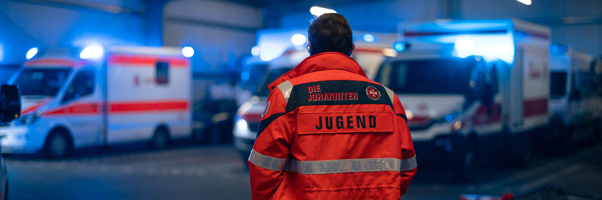 Eine Einsatzkraft der Johanniter-Jugend steht in der Fahrzeughalle der Johanniter in Wiesbaden.