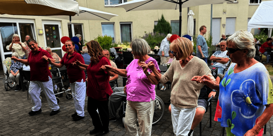 Eine Reihe Menschen hält sich tanzend an den Händen.