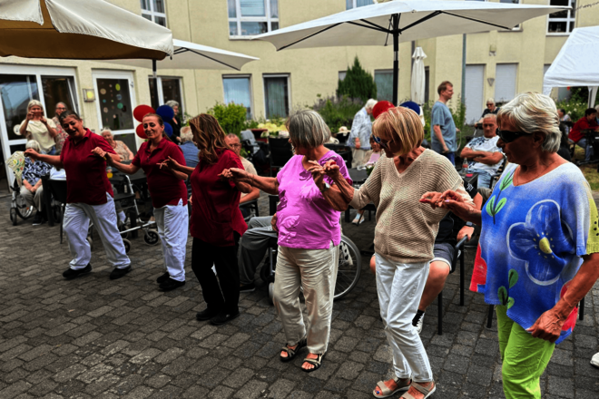 Eine Reihe Menschen hält sich tanzend an den Händen.