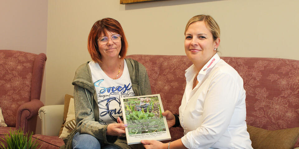 Zwei Frauen sitzen auf einem Sof und halten ein Bilderbuch in der Hand