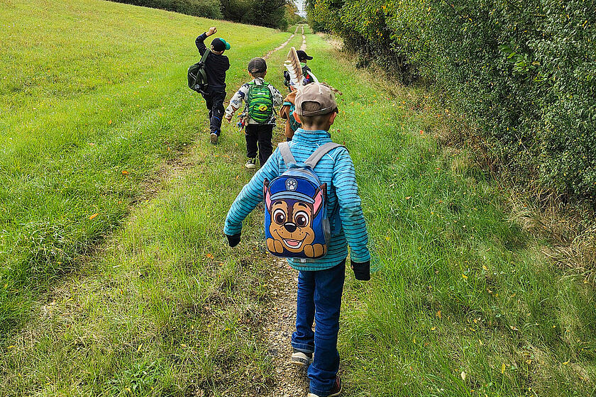 Kinder gehen an einem Feld entlang.