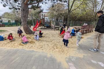 Kinder spielen in einem großen Sandspielplatz.