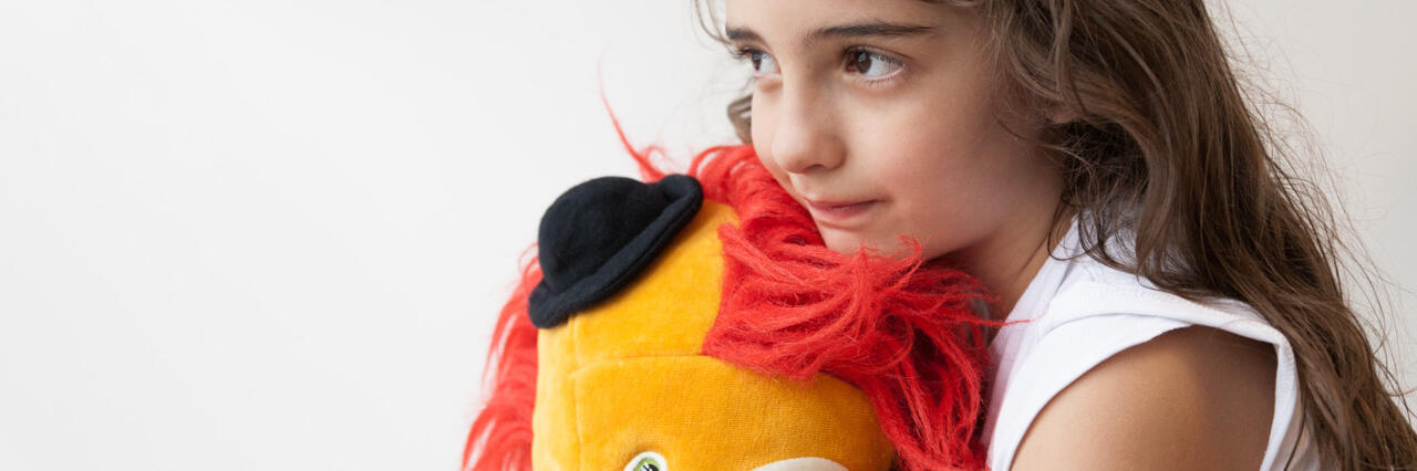 Kind umarmt Clown-Puppe – ein stiller Moment in der Trauerarbeit.