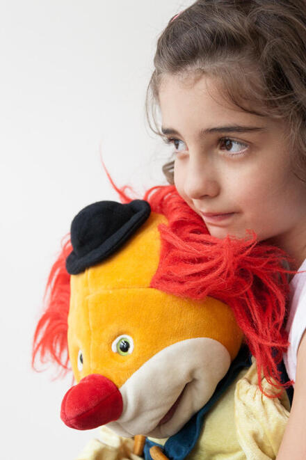 Kind umarmt Clown-Puppe – ein stiller Moment in der Trauerarbeit.