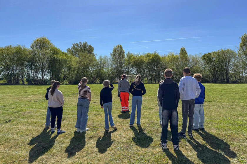 Eine Frau in Einsatzkleidung mit Kindern auf einer Wiese.
