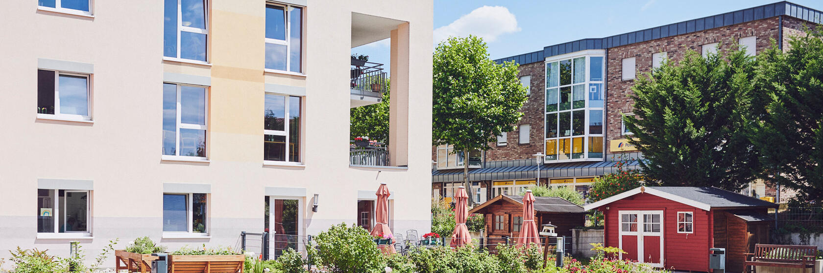 Blick auf die Fassade mit Sitzgelegenheiten und schönen Grünflächen davor