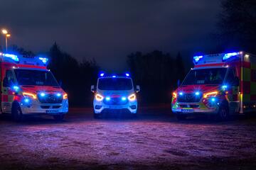 Drei Einsatzfahrzeuge stehen im Halbkreis, es ist dunkel