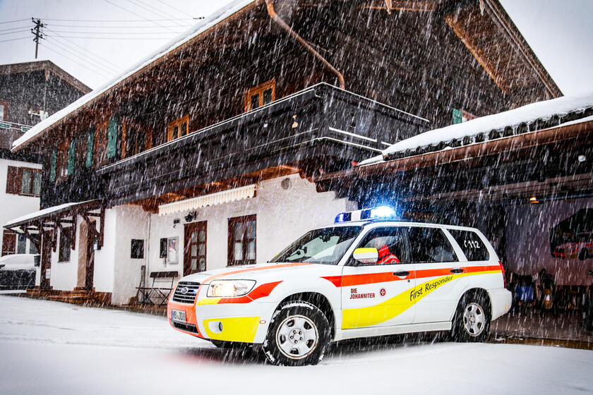 Johanniter-Einsatzfahrzeug startet bei Schnee aus der Garage zum Notruf