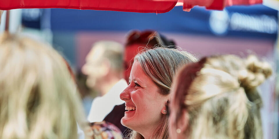 Eine Johanniter-Mitarbeitern hört lächelnd bei einer Rede zu 