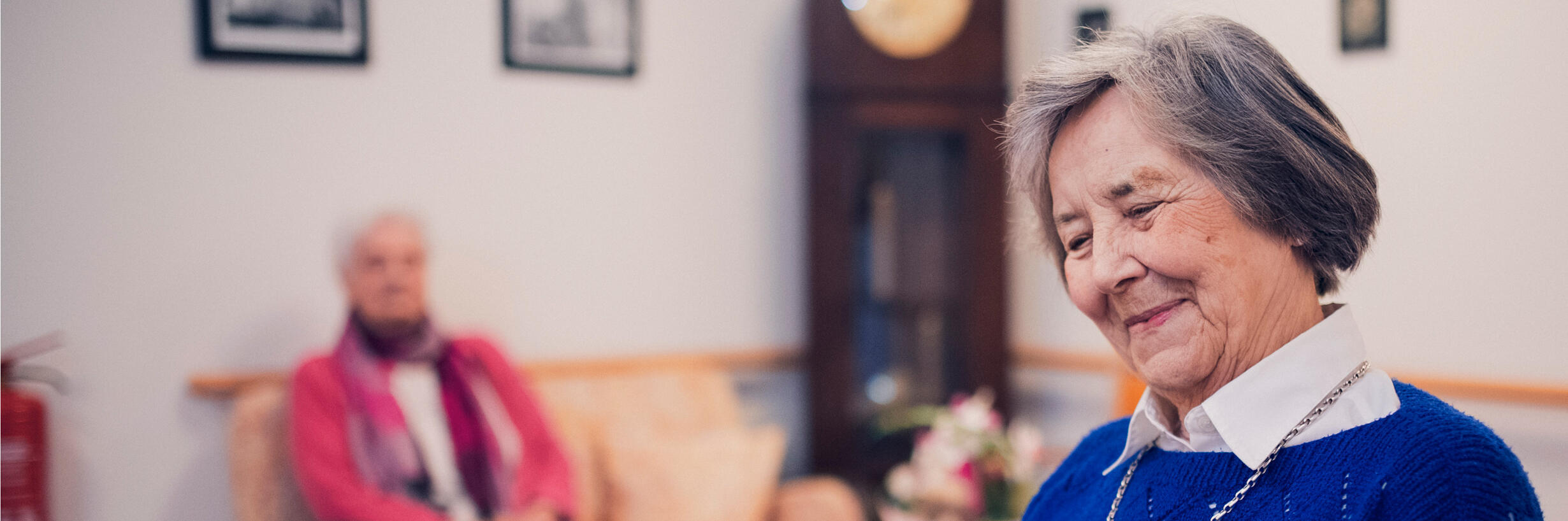 Eine Bewohnerin in blauem Pullover liest im Johanniter-Stift