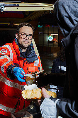 Ein Helfender des Kältebus gibt Essen an eine bedürftige Person aus