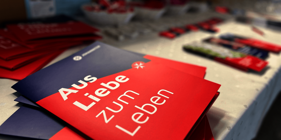 mehrere Broschüren, außen rot und blau, liegen auf einem Tisch aus