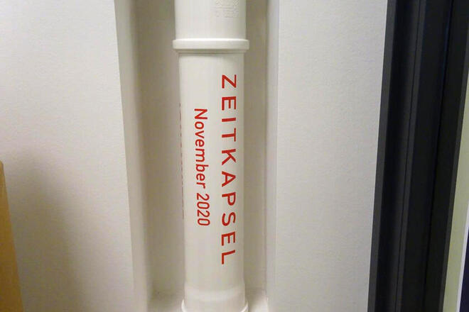 Zeitkapsel in weiß mit Name der Kita und Datum.