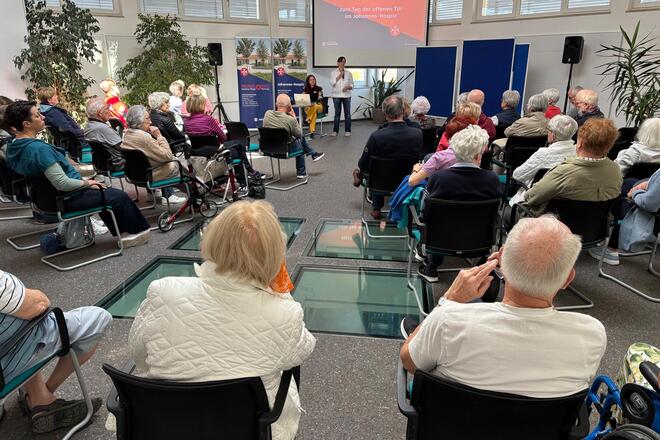 Besucher des Tages der offenen Tür sitzen im Seminarraum und werden von Einrichtungsleitung und Pflegedienstleitung begrüßt