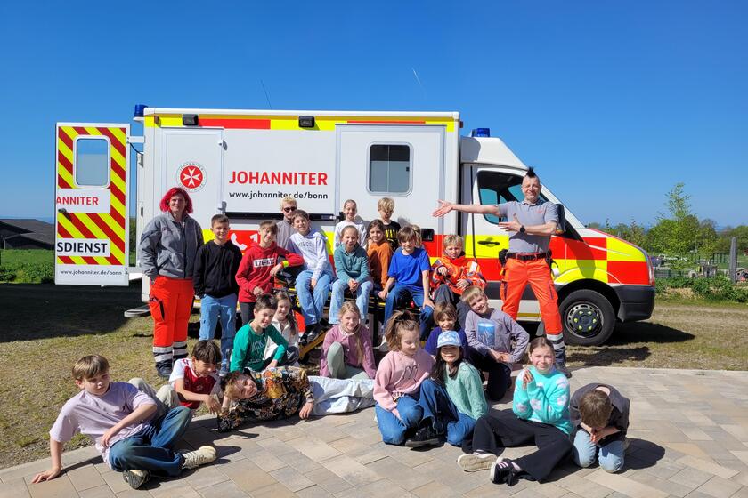 Die Kinder der Grundschule Lohmar Birk posieren vor dem Rettungswagen