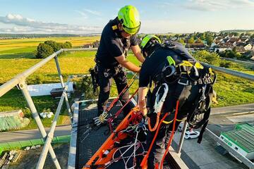 Höhenretter sind in Aktion und befestigen eine Trage um eine Person abzuseilen