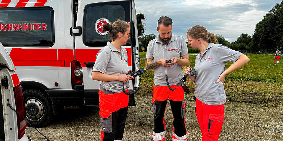 Drei Mitglieder der Rettungshundestaffel schauen auf ein Tablet