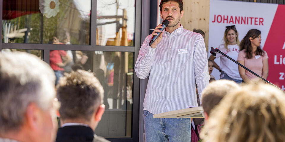 Einrichtungsleiter Johannes Kern spricht ins Mikrofon und begrüßt die Gäste.