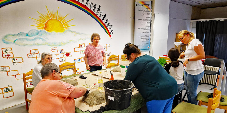 Frauen basteln mit Beton Tränken für Wildvögel an einem Tisch