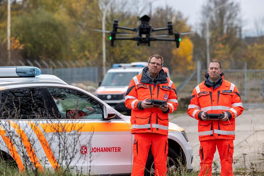 Zwei Männer mit einer vor ihnen schwebenden Drohne