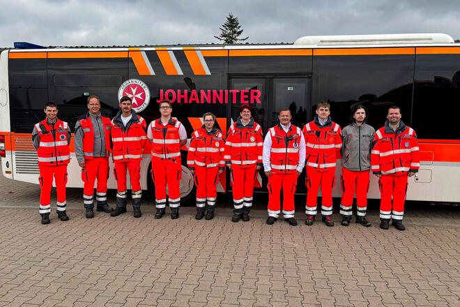 Zehn Frauen und Männer in Johanniter-Einsatzkleidung vor einem Johanniter-Bus