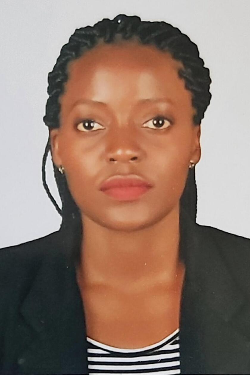 Ein Porträt von Jane Nakanwagi. Sie ist eine schwarze Frau, trägt lange Braids, ein weiß-schwarz gestreiftes Shirt und einen schwarzen Blazer