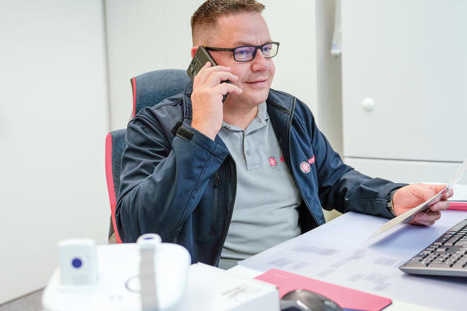 Ein Johanniter sitzt am Schreibtisch und telefoniert.