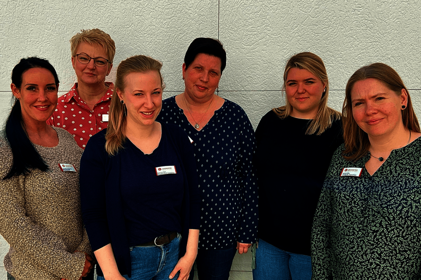 Sechs Frauen lächeln in die Kamera.