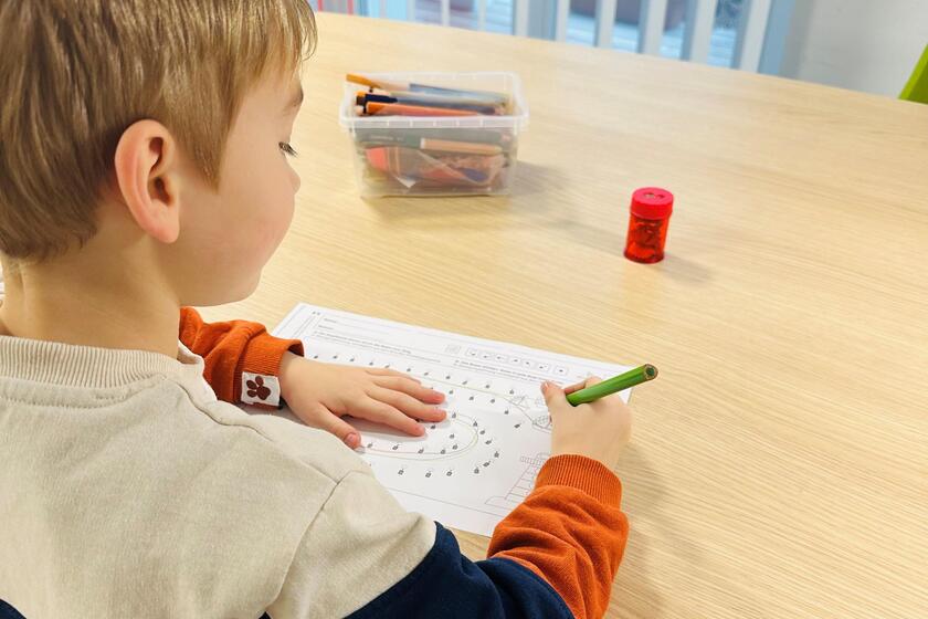 Ein Kind sitzt am Schreibtisch und malt.