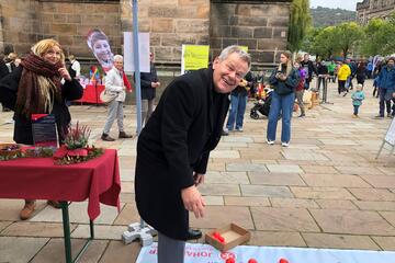 Männliche Person (OB Thomas Spies) legt Herz auf Mitmachplane ab