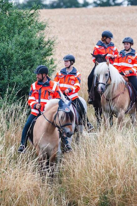 Mehrere Einsatzkräfte der Johanniter sitzen auf Pferden.