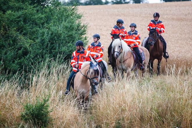 Mehrere Einsatzkräfte der Johanniter sitzen auf Pferden.
