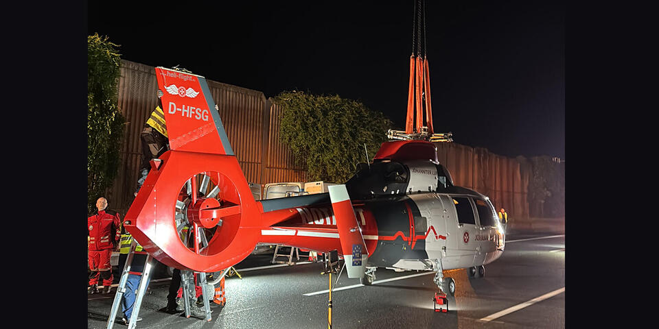 Der Kran hebt den Hubschrauber an.