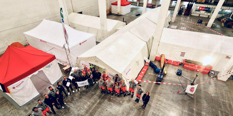 Drohnenaufnahme aus der Höhe vom Team bei der Zertifizierung des EMT der Johanniter mit der Base of Operation im Hintergrund.