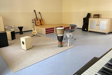 Ein Raum gefüllt mit Saiteninstrumenten, Trommeln und einem Klavier.