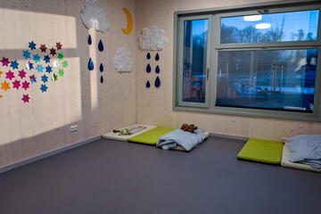 Ruheraum der Kinderkrippe mit Matratzen, Kissen und Wanddeko aus Sternen und Wolken.