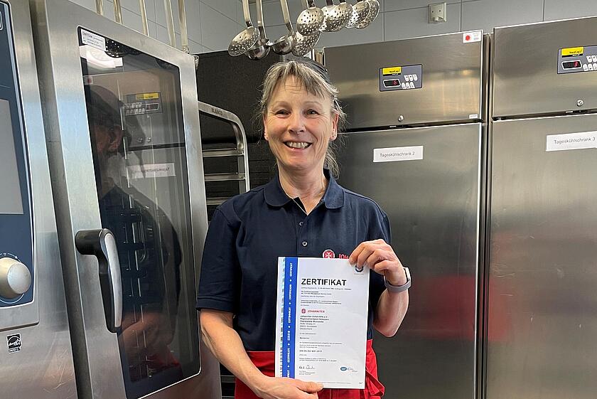 Frau hält TÜV-Zertifikat hoch