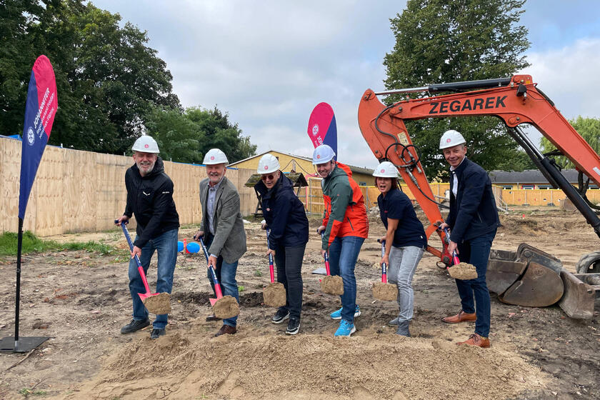 Herr Ryl, Wiegard, Hemmerling und Boost sowie Frau Andexer und Maager schaufeln fröhlich etwas Sand in Richtung der Kamera zum Ersten Spatenstich.